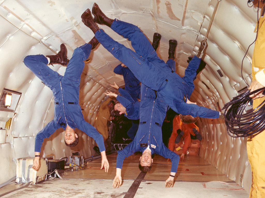 Several astronauts floating upside-down in a microgravity environment