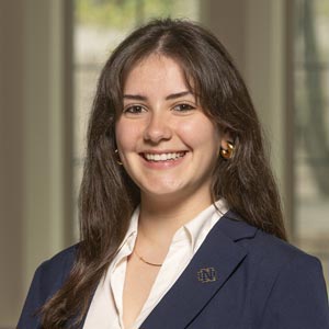 Headshot of Celeste Mannel, SWE Social Media Chair, wearing a navy blazer and white blouse, smiling in front of a softly blurred indoor background.