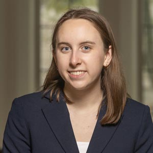 Headshot of Kate Heitmann, SWE Mentorship Director, wearing a navy blazer over a white top, smiling in front of a softly blurred indoor background.