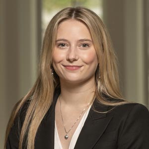 Headshot of Katherine Comito, SWE Saint Mary’s Liaison, wearing a black blazer over a white blouse, smiling in front of a softly blurred indoor background.