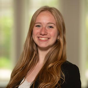 Headshot of Kylie Staebler, SWE Inter-SWE Liaison, wearing a black blazer over a white top, smiling in front of a softly blurred indoor background.