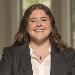 Headshot of Lillian Nadler, SWE Corporate Sponsorship Co-Director, wearing a dark blazer over a white blouse, smiling in front of a softly blurred indoor background.
