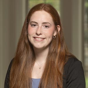 Headshot of Maggie Kelley, SWE Professional Development Director, wearing a dark blazer over a lavender top, smiling in front of a softly blurred indoor background.