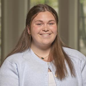 Headshot of Melanie Carney, SWE Social Co-Director, wearing a light blue sweater, smiling in front of a softly blurred indoor background.