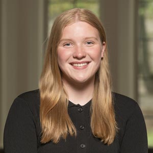 Headshot of Peyton Honchar, SWE Recruitment Co-Director, wearing a black sweater, smiling in front of a softly blurred indoor background.