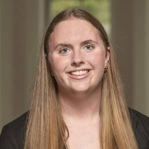 Headshot of Taryn Wilson, SWE Social Co-Director, wearing a black top, smiling in front of a softly blurred indoor background.