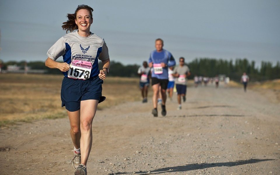 A woman running a race bursts ahead of her male competitors while smiling.