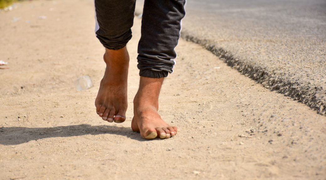 barefoot person walking outdoors during the day