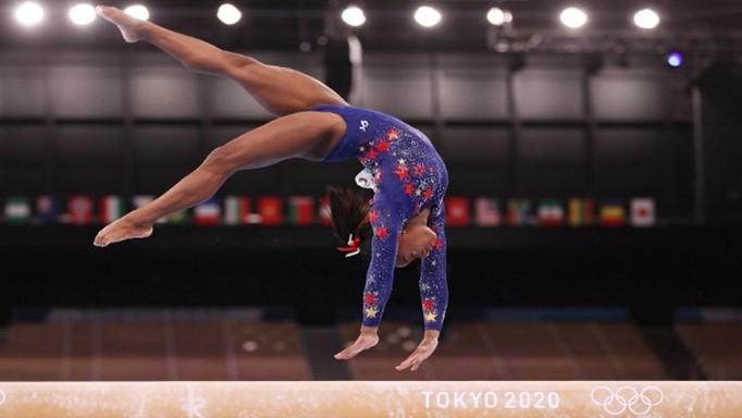 Simone Biles doing a back handspring on the beam at the Tokyo Olympics.