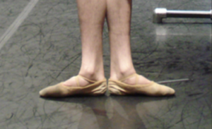 Ballet dancer's feet in first position, with each set of toes turned out away from the center line of the body.