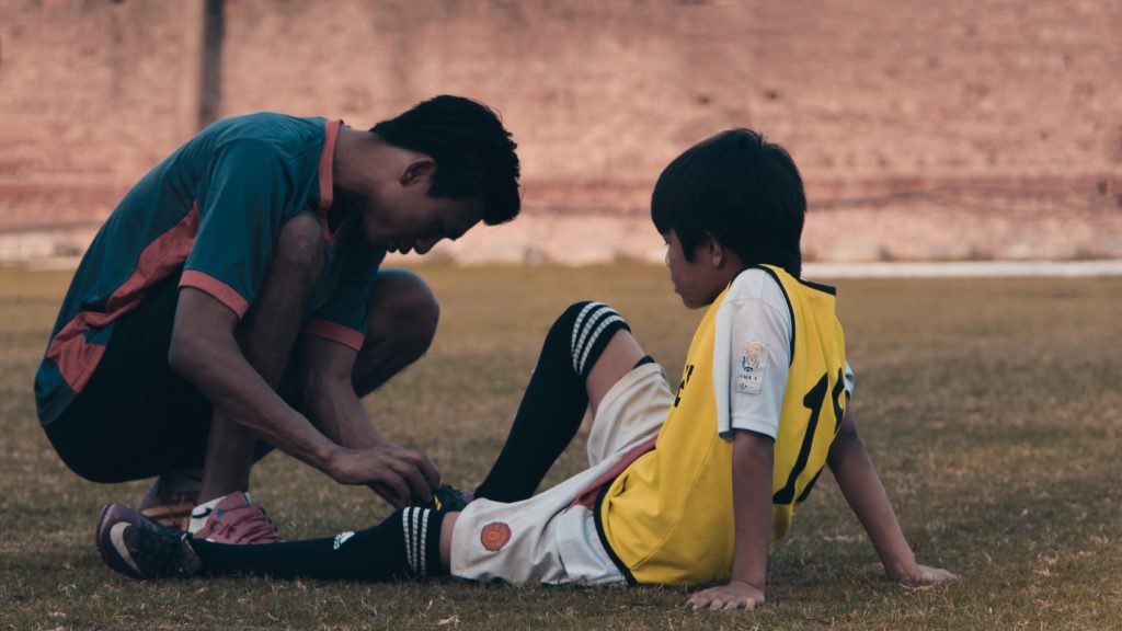 A young athlete receives medical treatment from a coach.