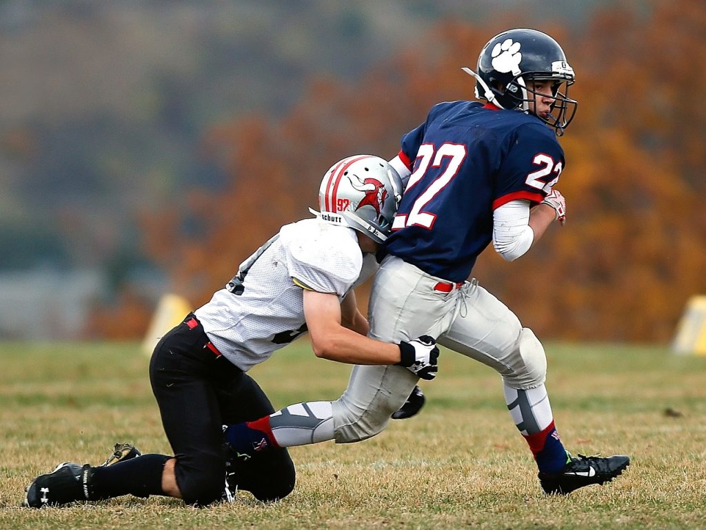 an opposing team's football player tackling another football player by the legs