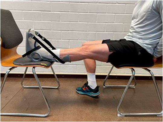 Man performing a static stretch of his calf using a stretching device while seated.