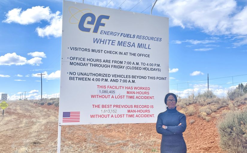 Female student standing in front of a sign for the White Mesa mill