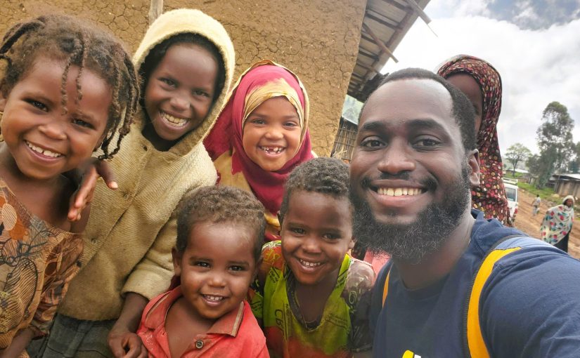 the author pictured smiling with five local children in a village in Ethiopia