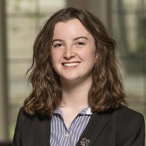 Portrait of Maggie Howard, Fall Executive Vice President of Notre Dame SWE, smiling and wearing a black blazer and blue striped shirt.